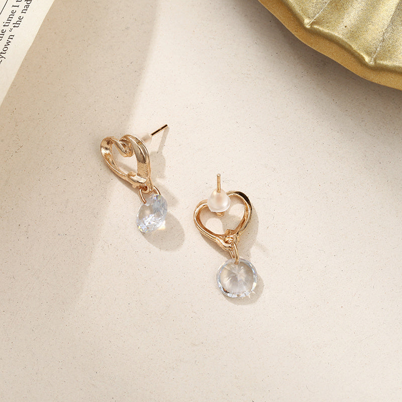 a pair of gold earrings with a heart shaped stone and a pearl