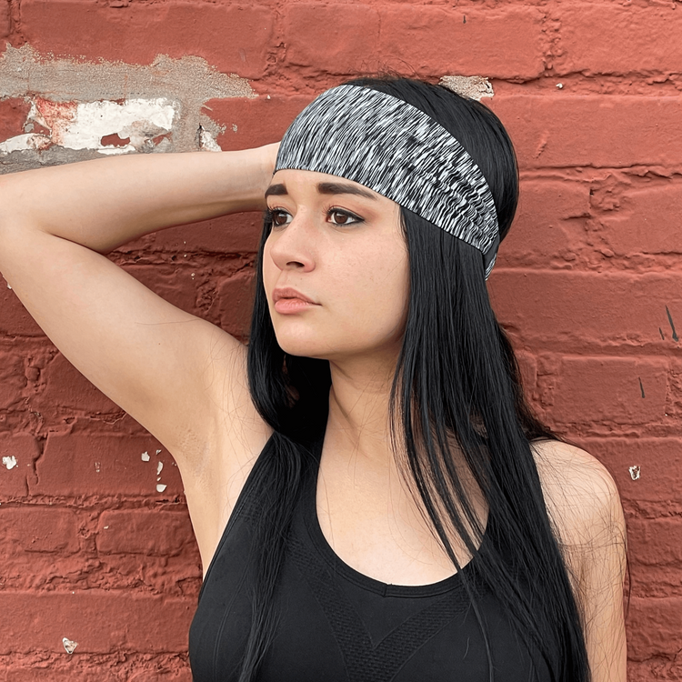 a woman with black hair and headband leaning against a brick wall