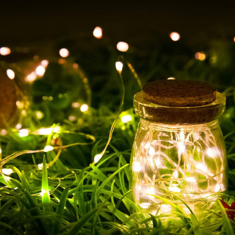 a jar with lights in the grass