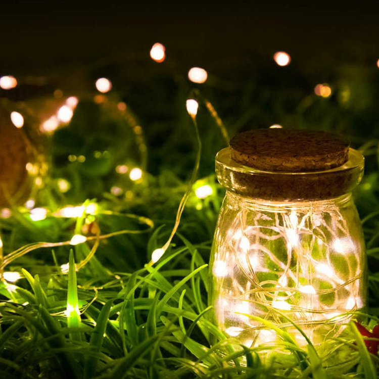 a jar with lights in the grass