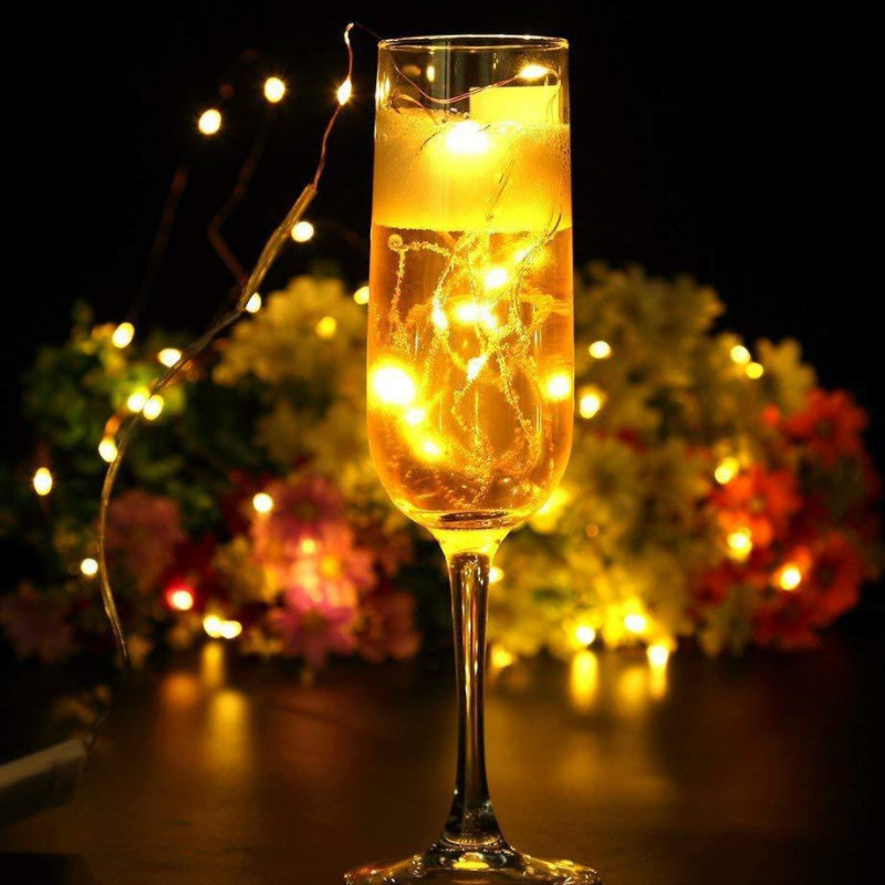 a glass of champagne with lights in the background