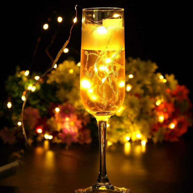 a glass of champagne with lights in the background
