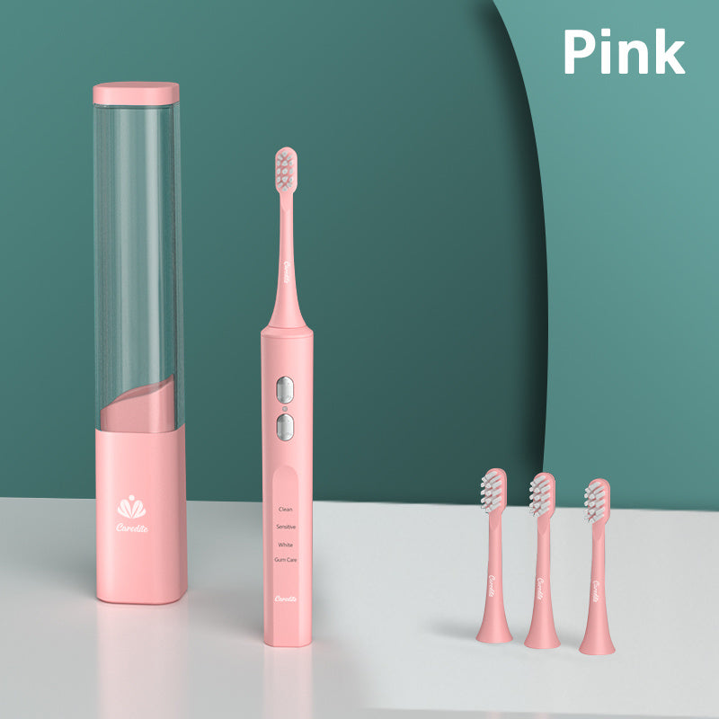 a pink electric toothbrush and a tube