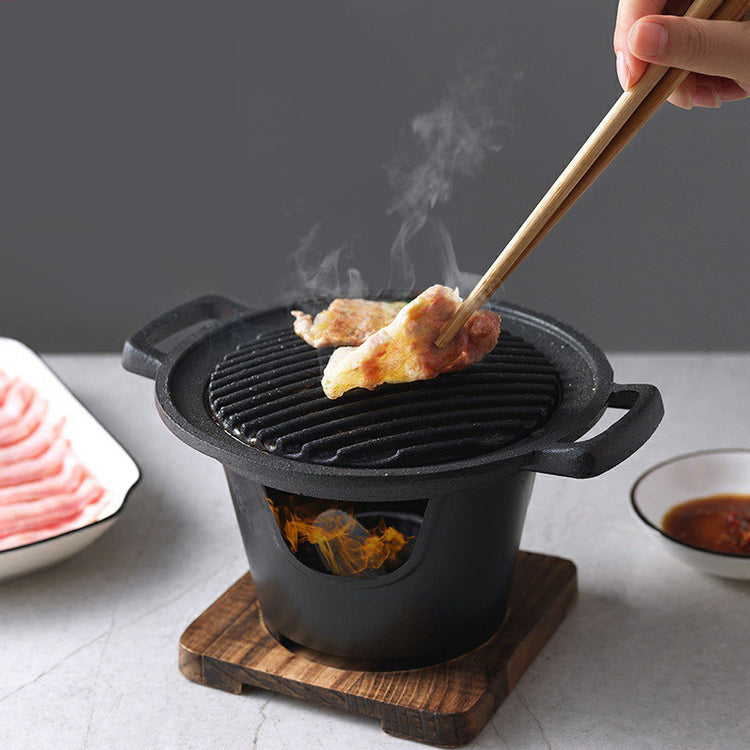 a person holding chopsticks over a grill