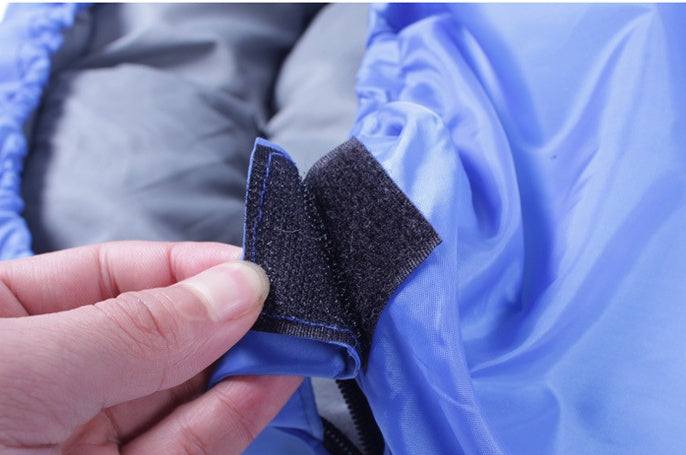 a hand holding a black velcro on a blue jacket