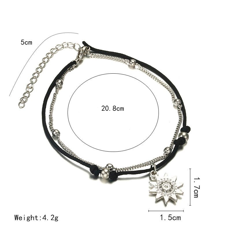 a black and silver bracelet with a silver sun pendant