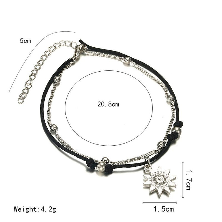 a black and silver bracelet with a silver sun pendant