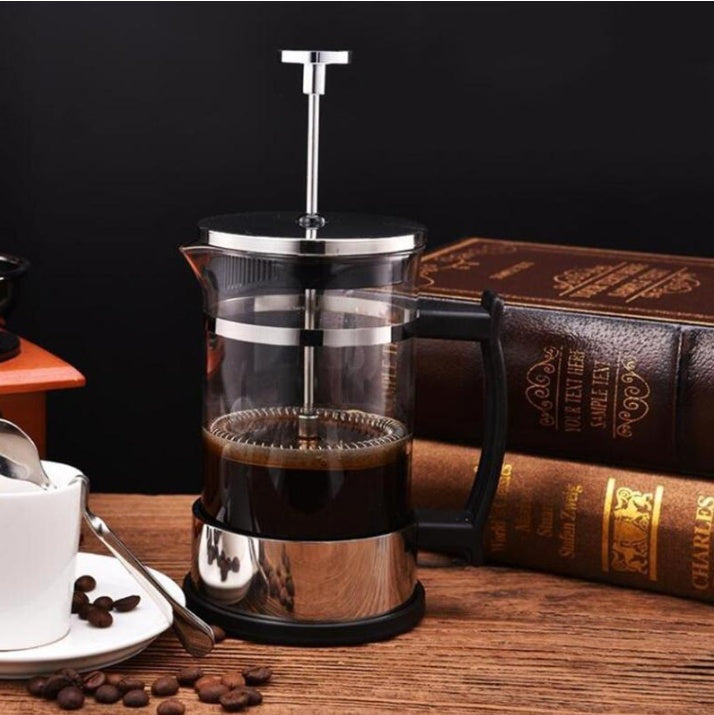 a coffee maker and a cup of coffee next to books
