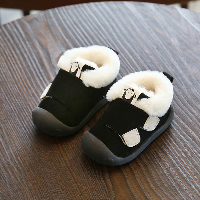 a pair of black and white baby shoes on a wood table