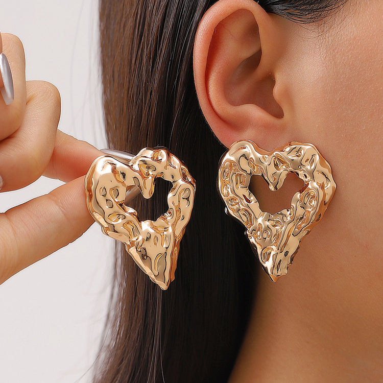 a woman wearing gold heart shaped earrings