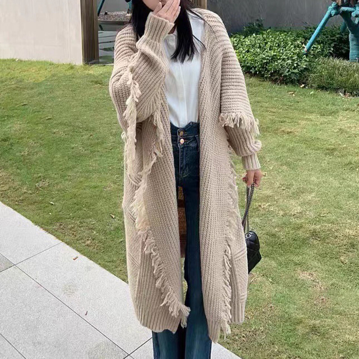 a woman in a long cardigan and hat