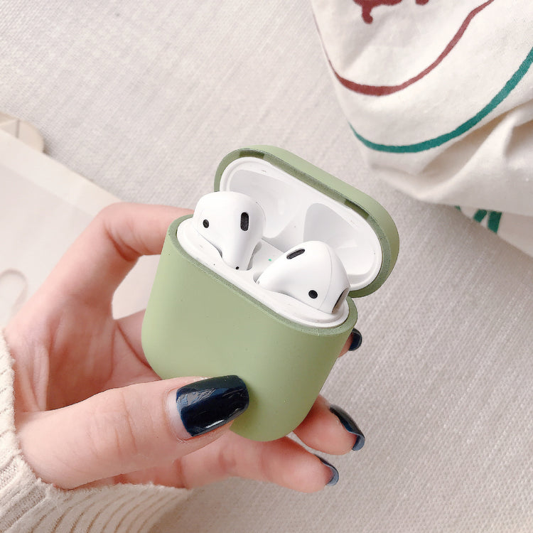 a hand holding a green case with two white headsets