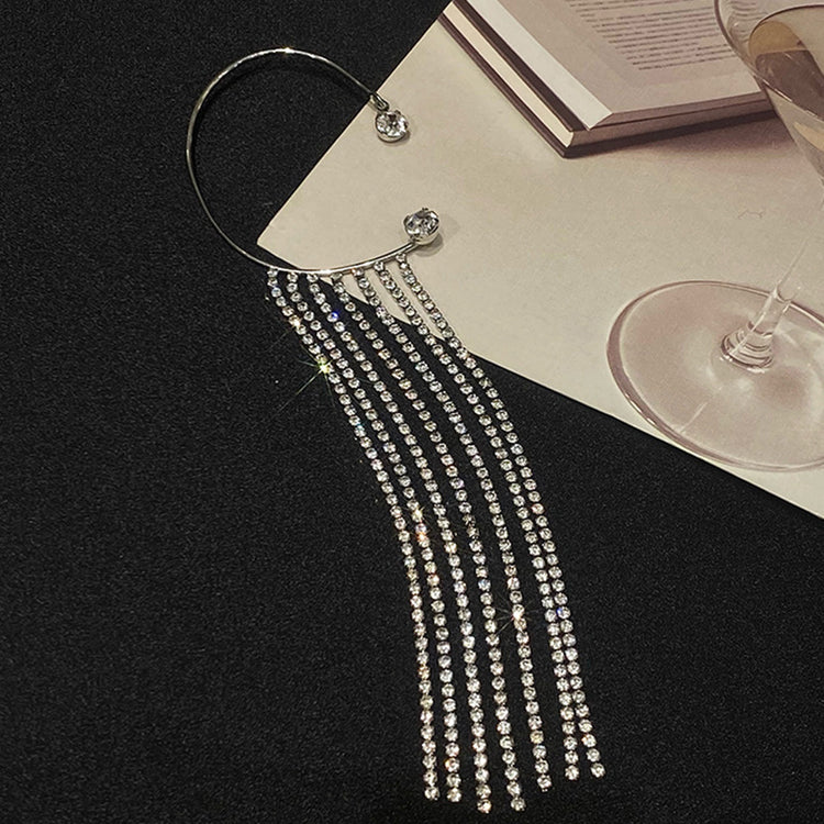 a silver hoop with rhinestones on it next to a glass of wine