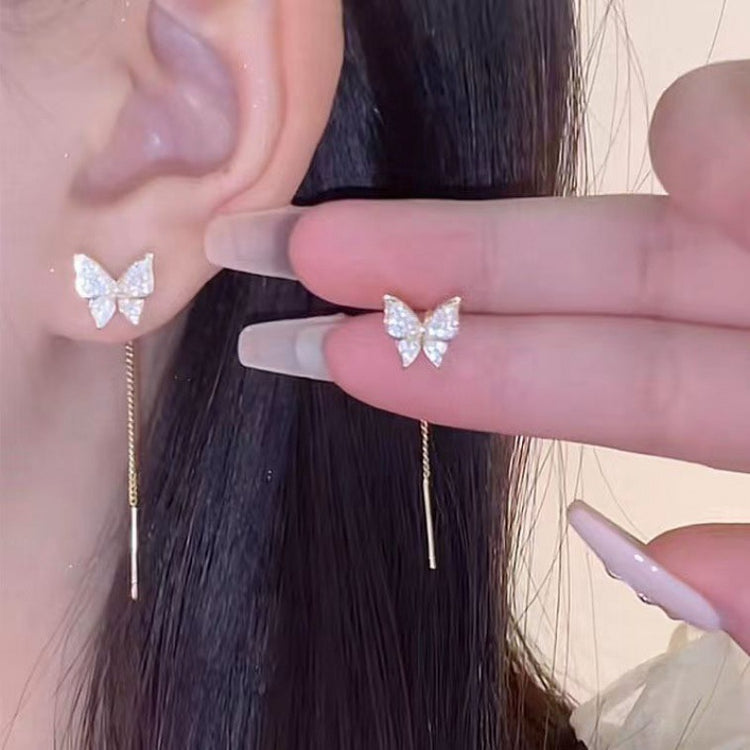 a person wearing earrings with a butterfly design