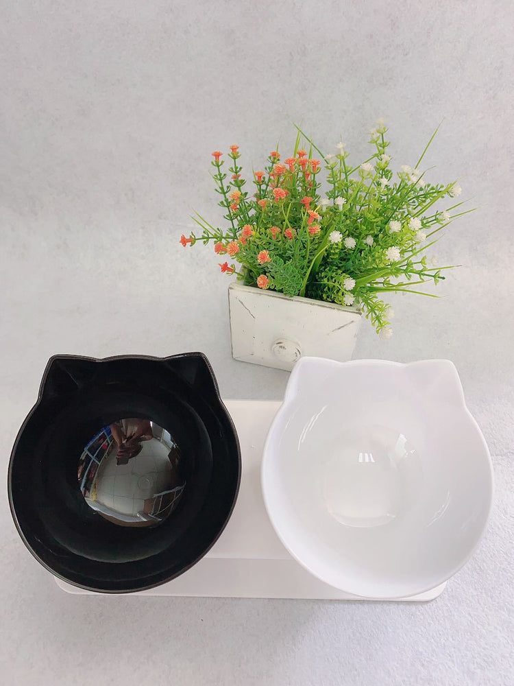 a cat shaped bowls next to a plant