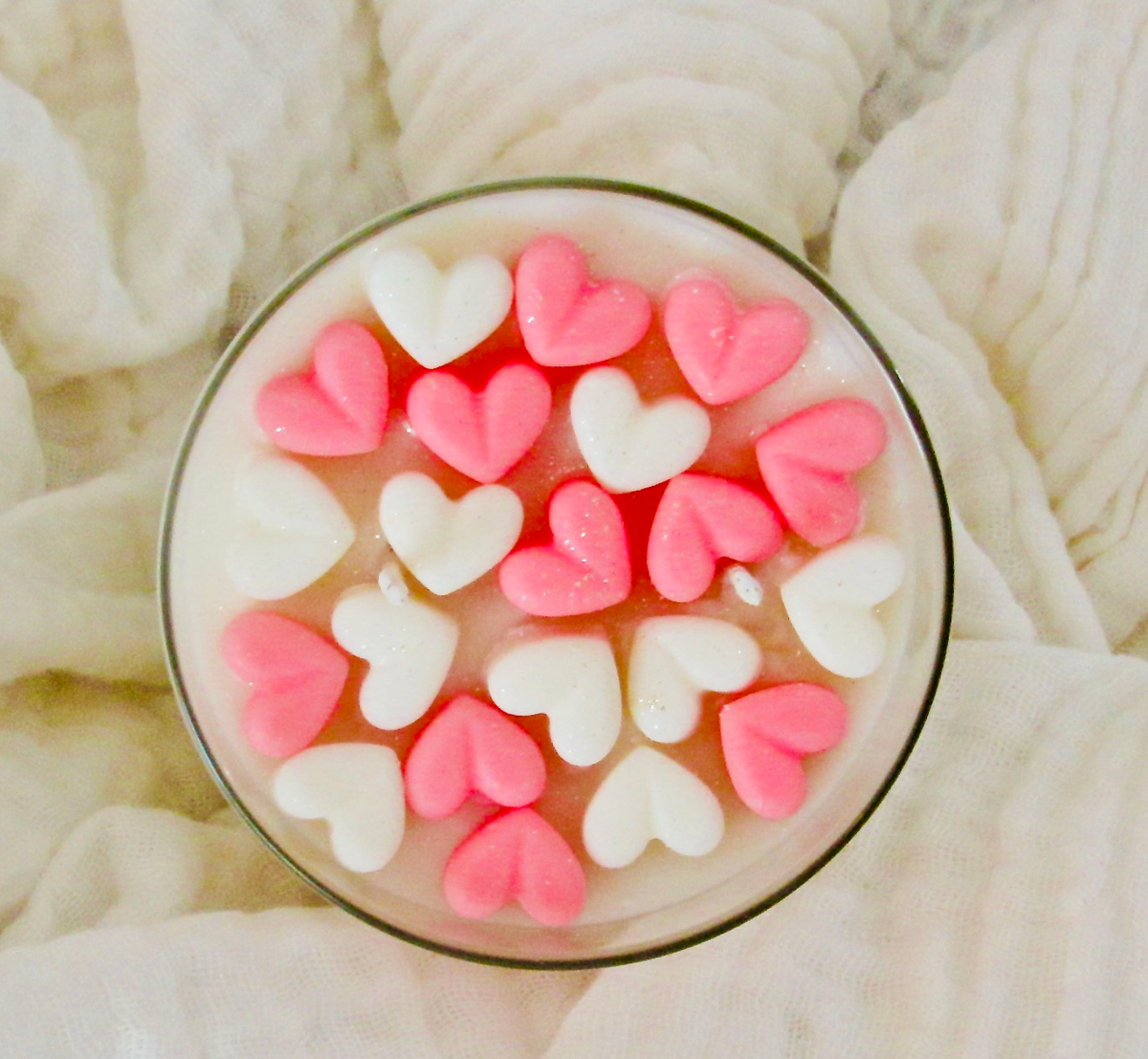 a bowl of pink and white hearts on a white blanket