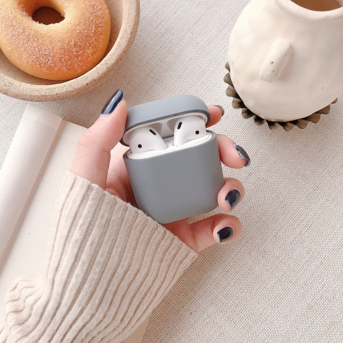 a hand holding a case with a couple of white earbuds