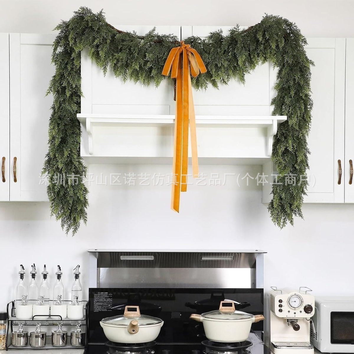 a kitchen with white cabinets and green garland