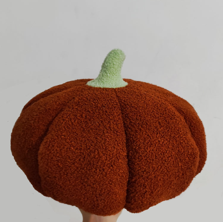 a hand holding a stuffed pumpkin