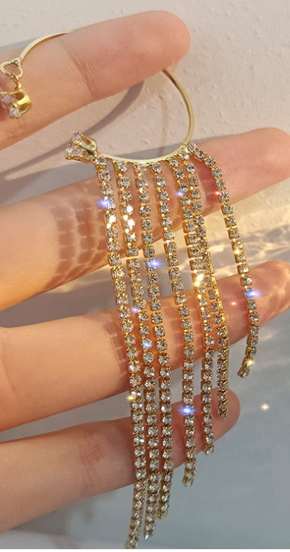 a hand holding a gold and diamond earring