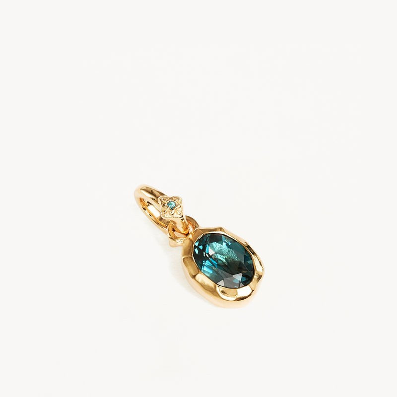 a gold pendant with a blue gem