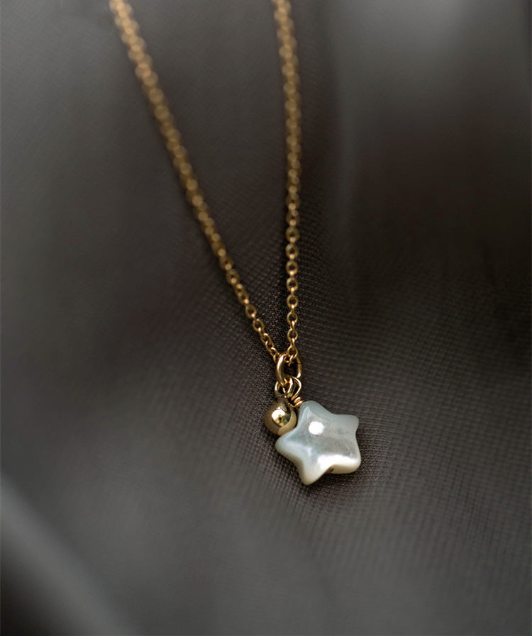 a gold star necklace with a pearl pendant