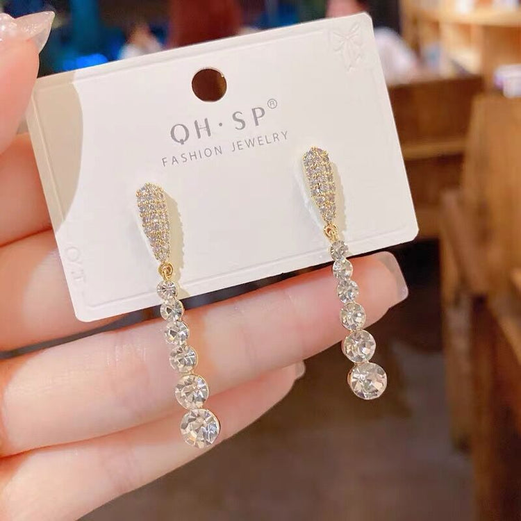 a hand holding a pair of earrings