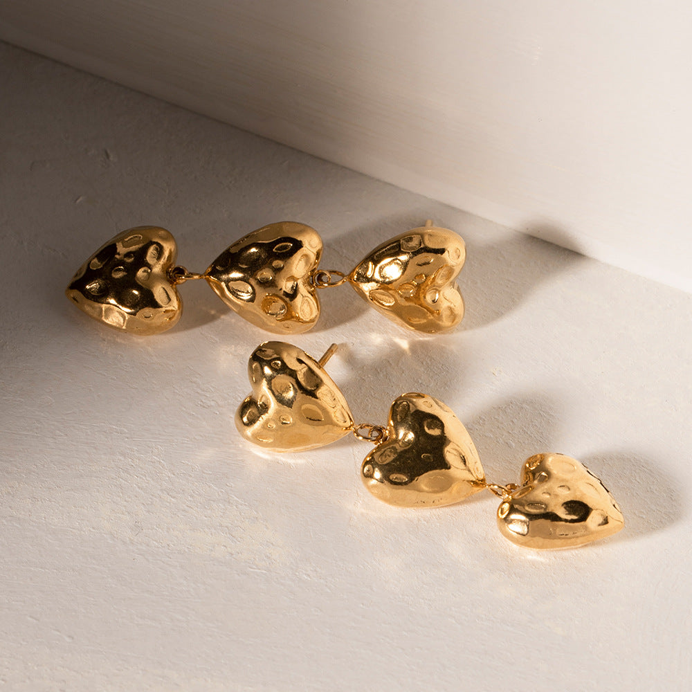 a pair of gold heart shaped earrings