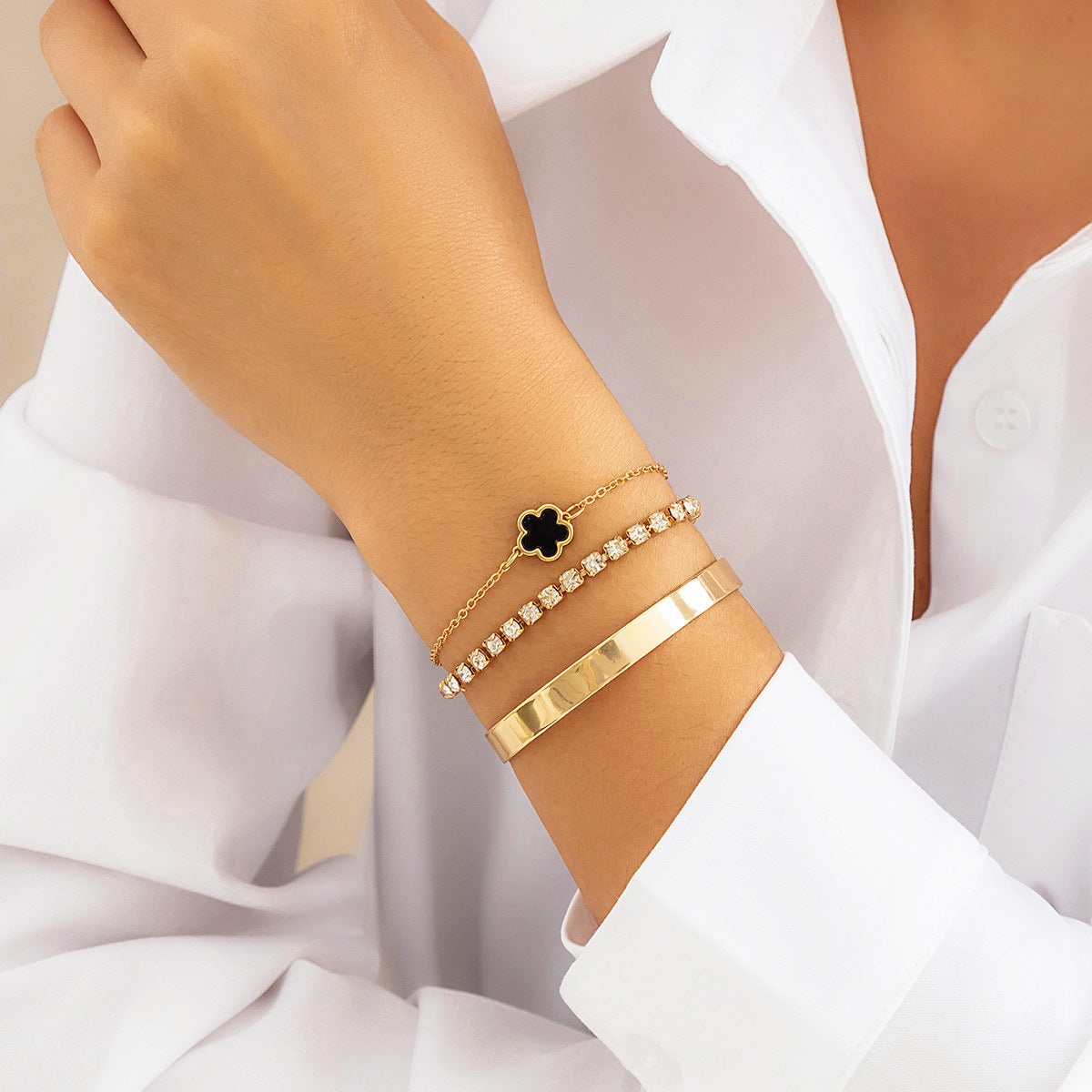 a person wearing a white shirt and gold bracelets