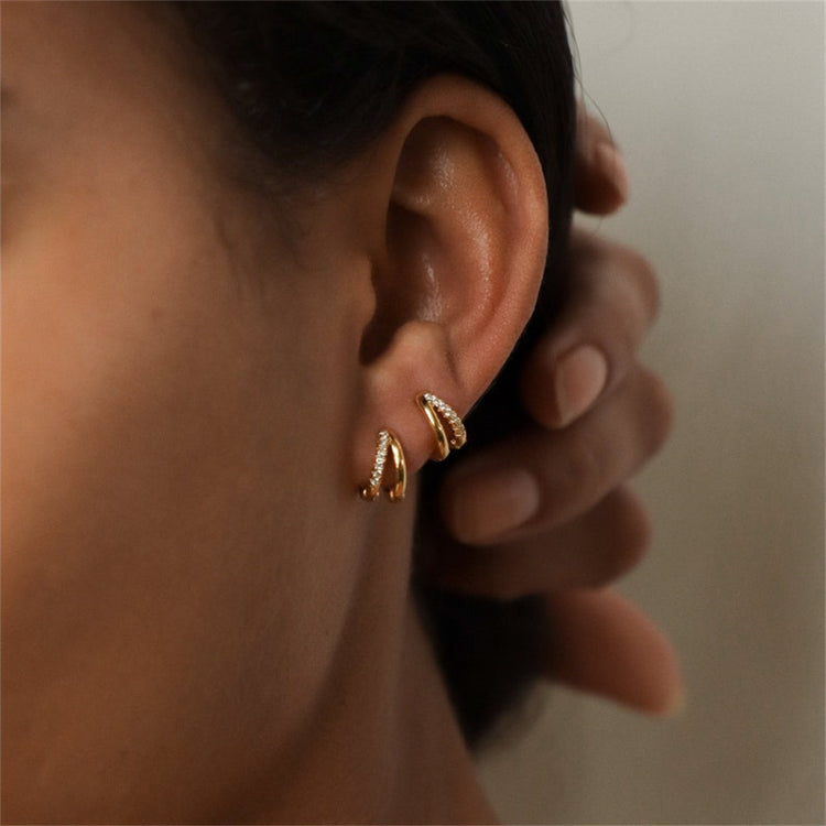 a person's ear with gold hoop earrings