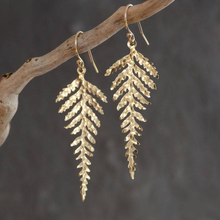 a pair of gold earrings on a branch