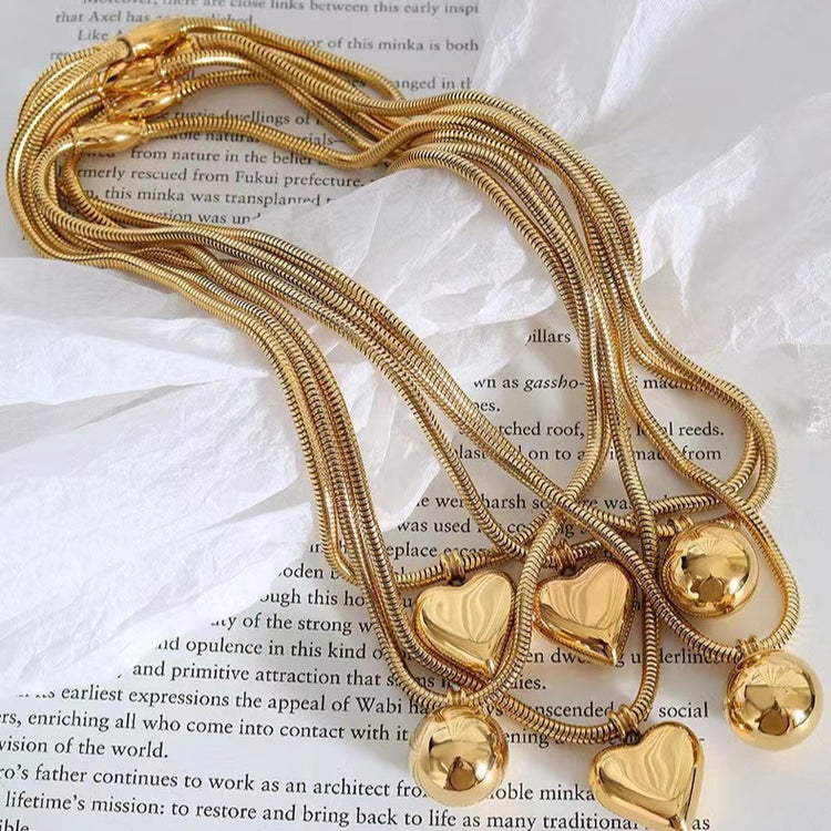 a gold necklace with heart shaped pendants on a piece of paper