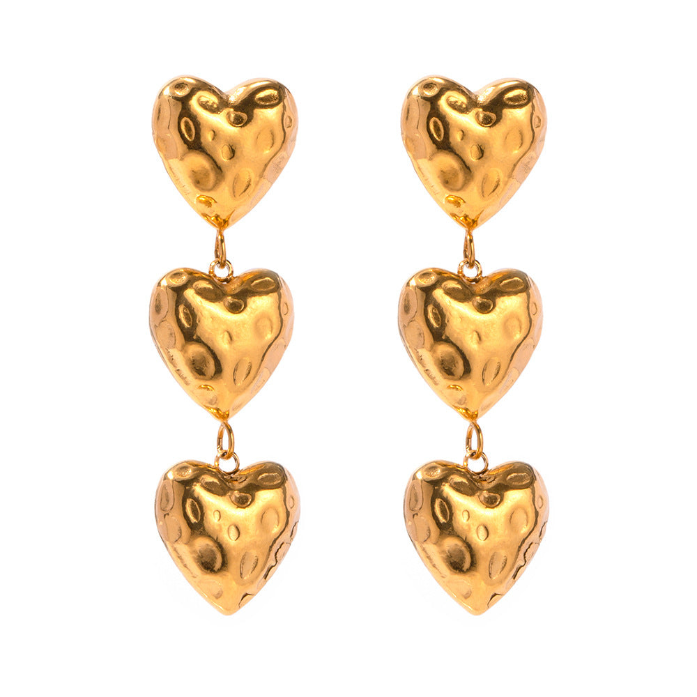 a pair of gold hearts earrings