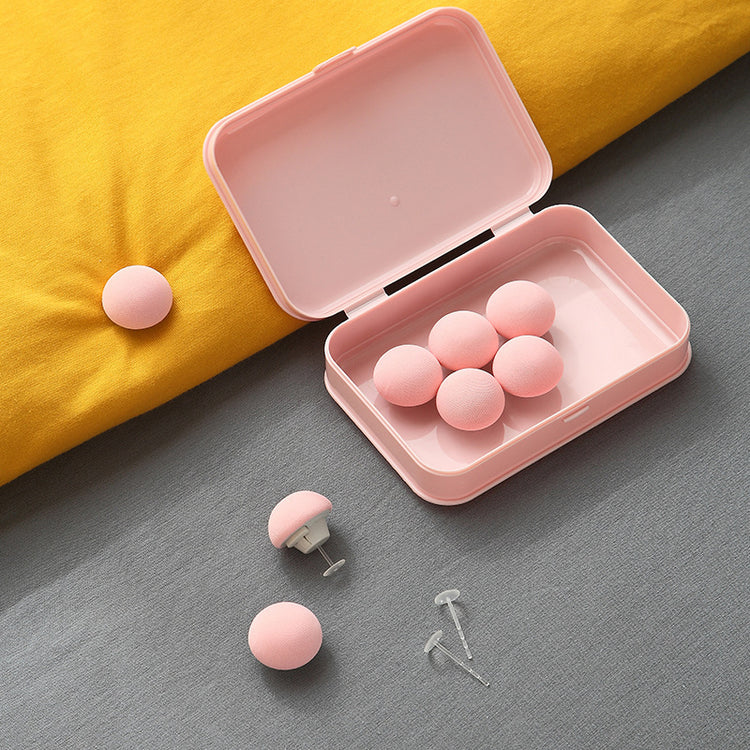 a pink container with round objects on it next to a yellow pillow