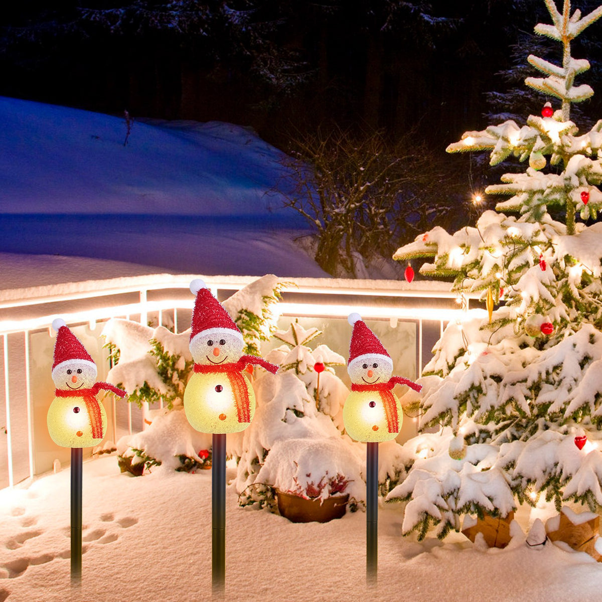 a group of snowmen and a tree in the snow