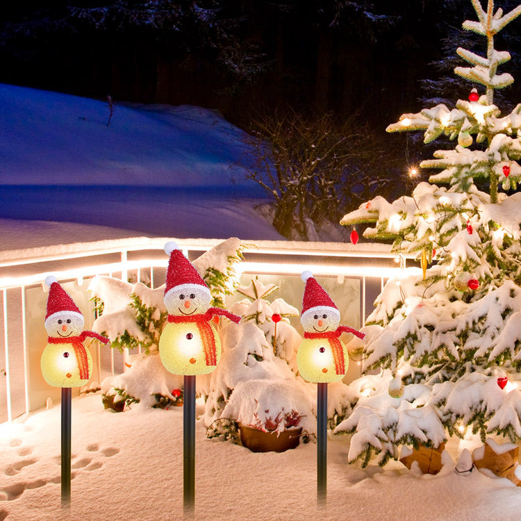 a group of snowmen and a tree in the snow
