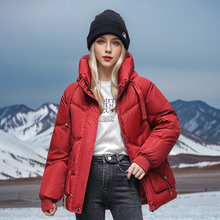 a woman in a red coat and hat standing in front of snow covered mountains
