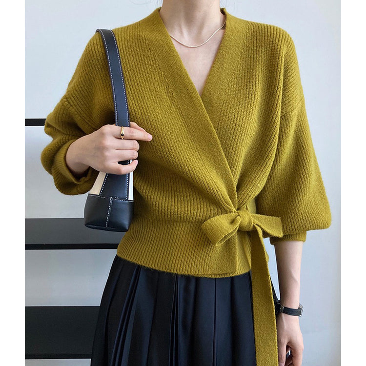 a woman wearing a green sweater and black skirt