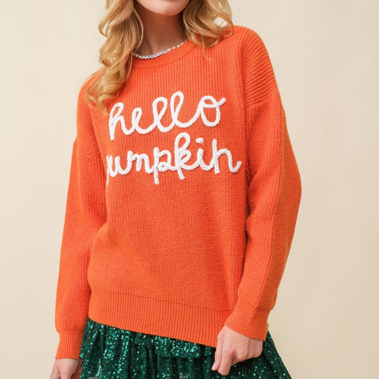 a woman in an orange sweater and green skirt