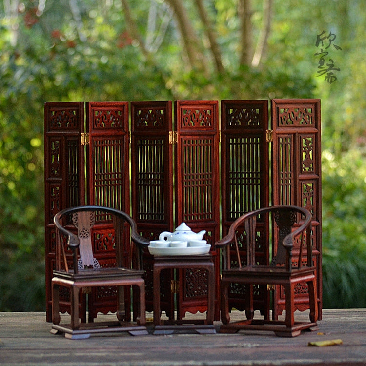 a tea set and chairs in front of a screen