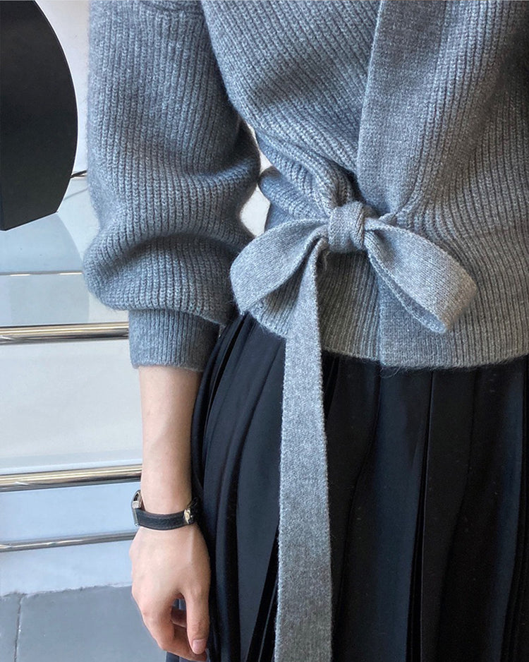 a person wearing a grey sweater and black skirt
