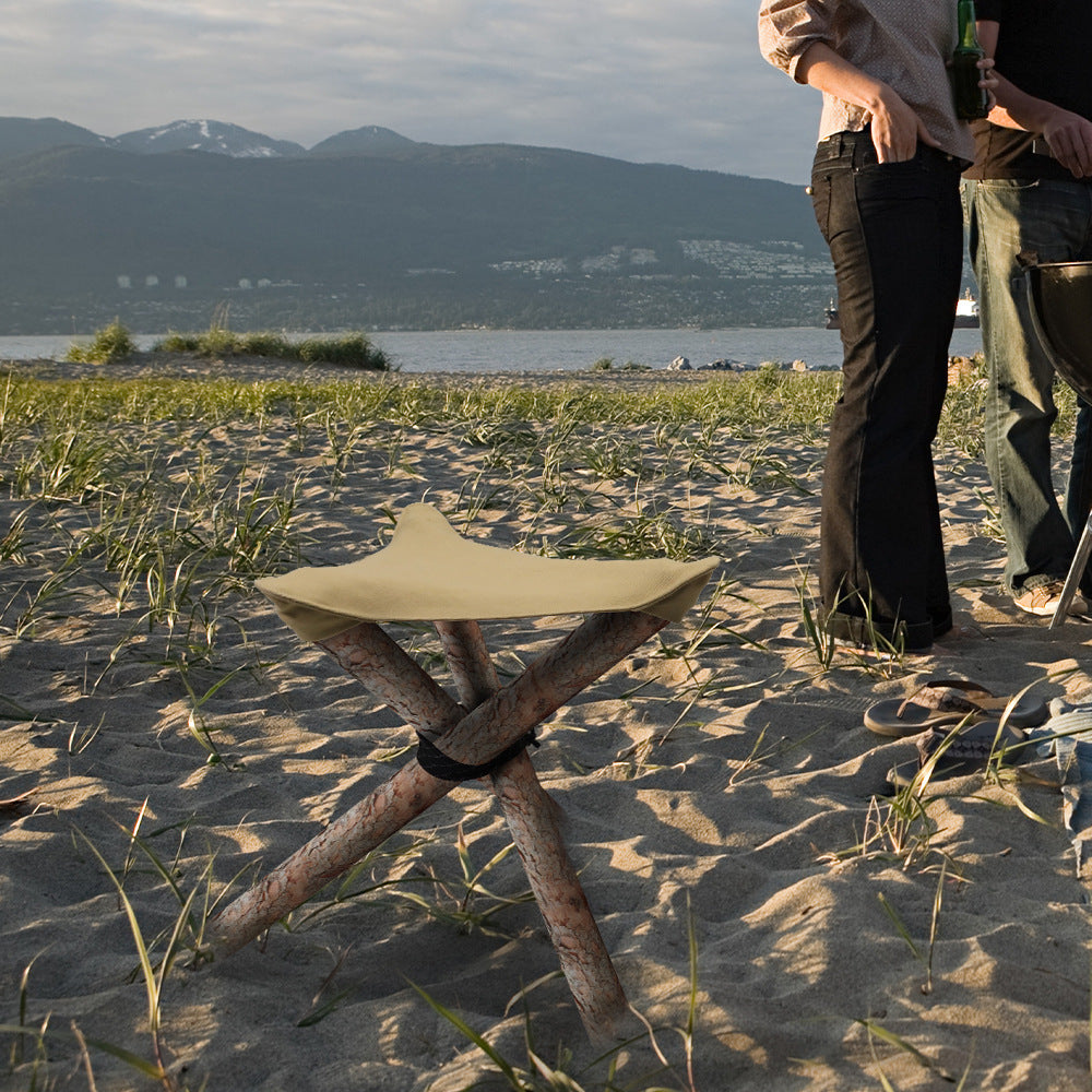 a person standing in the sand next to a stool