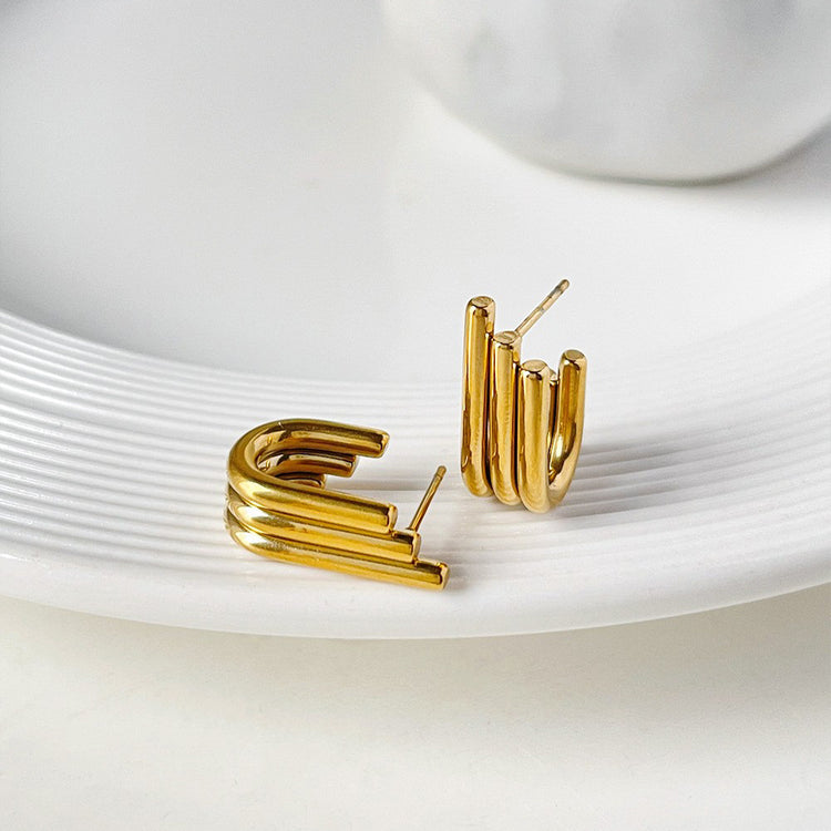 a pair of gold earrings on a white plate