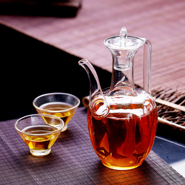 a glass jug with a glass lid and a couple small cups of liquid
