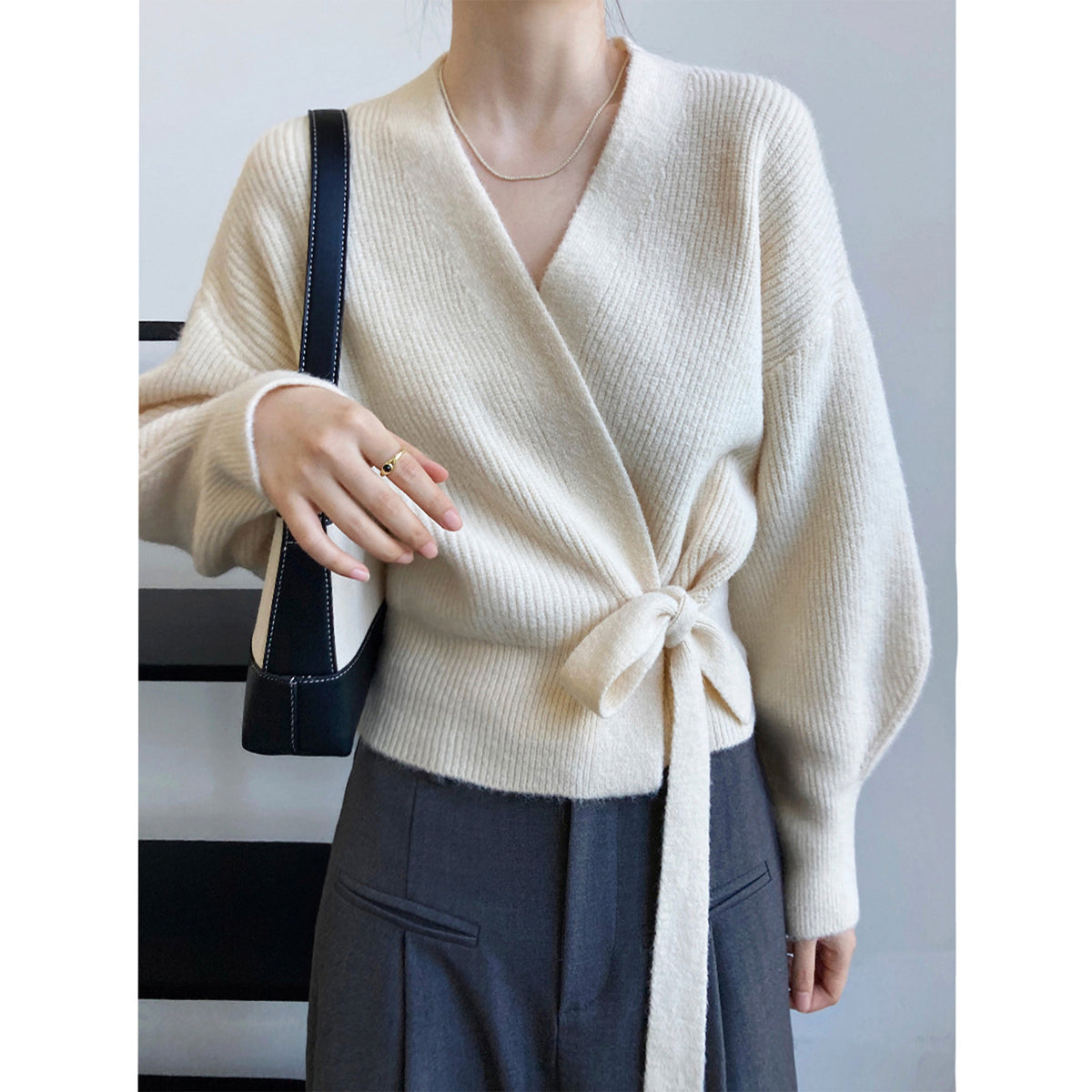 a woman wearing a white sweater and grey pants