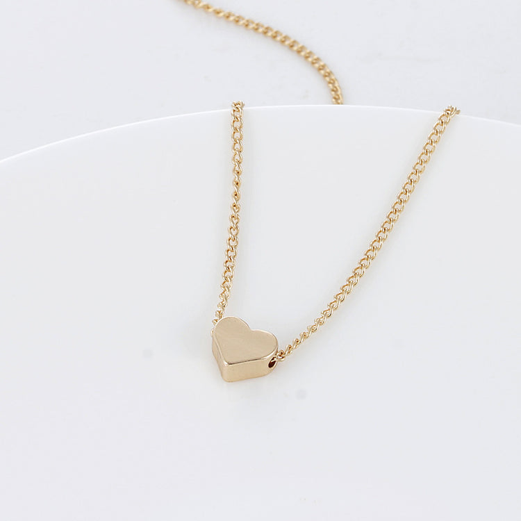 a gold heart necklace on a white plate