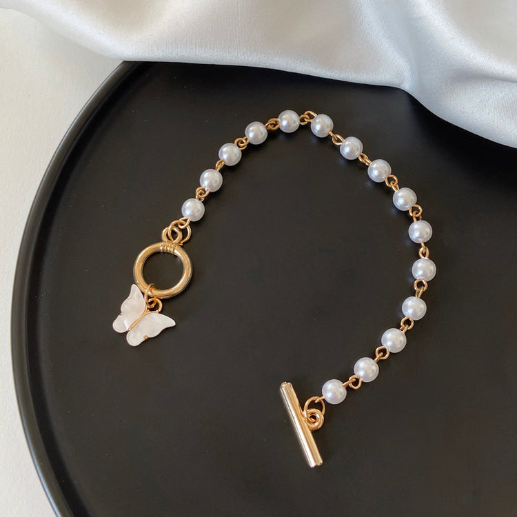 a bracelet with a butterfly charm on a black plate