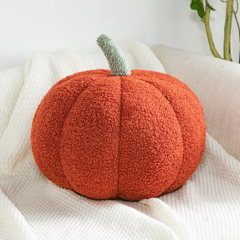 a pumpkin shaped pillow on a white blanket