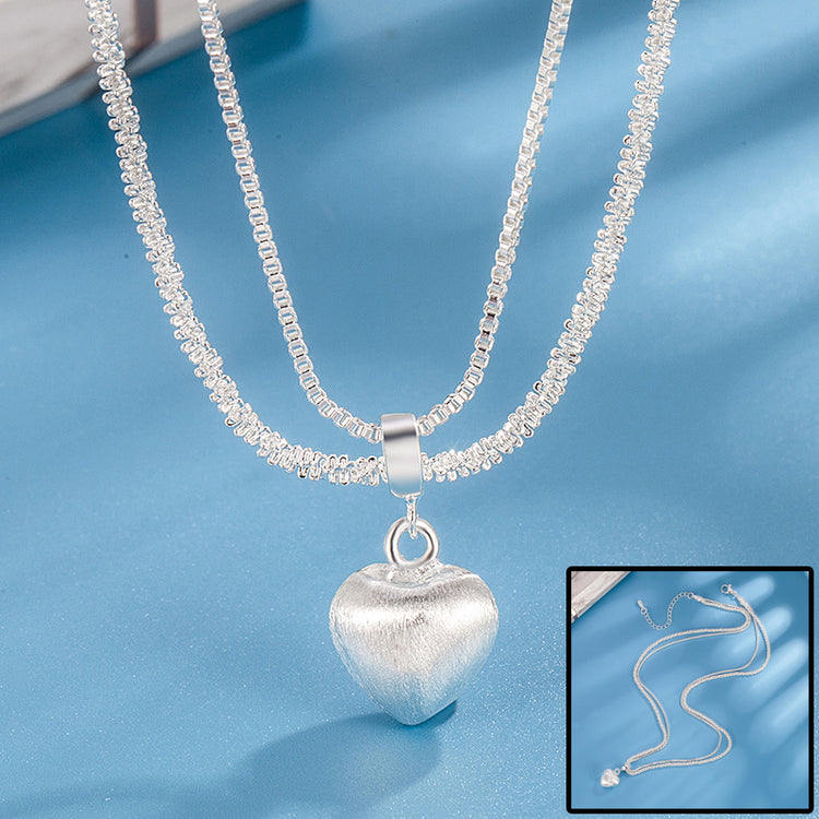 a silver heart necklace on a blue surface