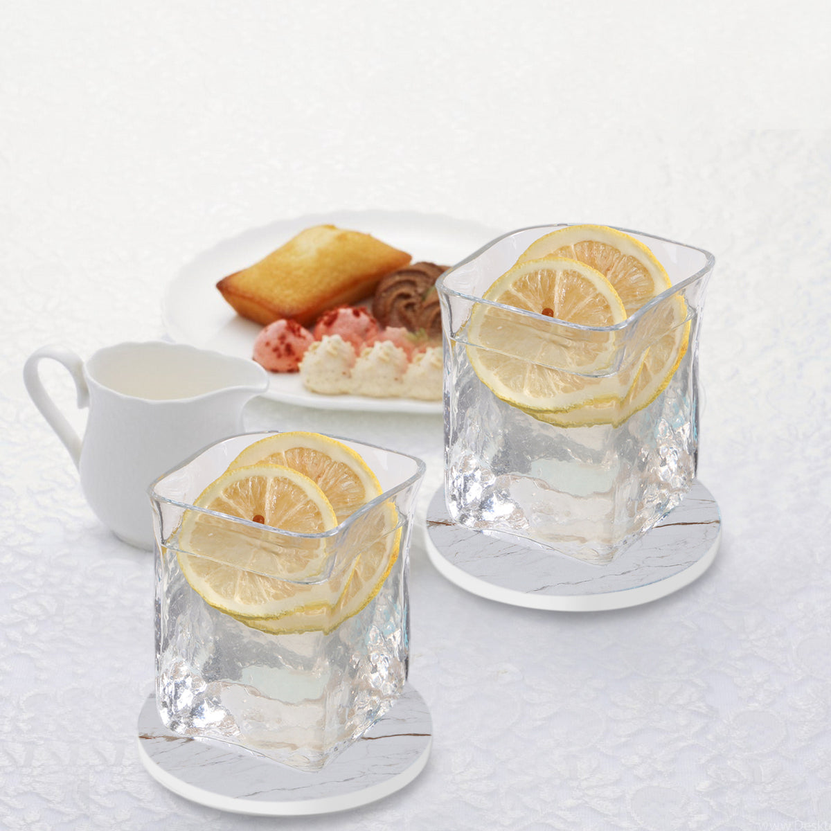 two glasses of ice water with lemon slices and a plate of dessert